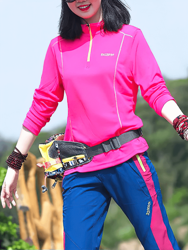 Woman in bright pink quick-drying top with half zip and stand-up collar, outdoorsy and ready for adventure.
